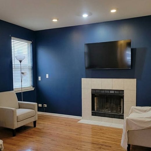 Living room after: deep navy accent walls around the fireplace and mounted TV